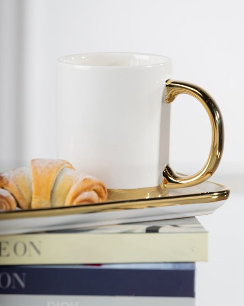 Kubek z łyżeczką Lana White Wykonany z ceramiki w kolorze białym ze złotymi krawędziami. Pojemność kubka wynosi 300 ml.